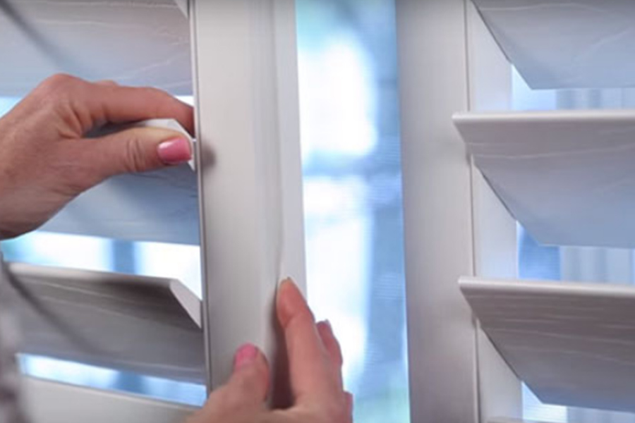 A woman's hands showing off weatherstripping on Polywood shutters on a window