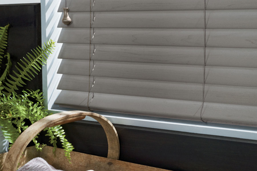 Custom wood and faux wood blinds fit your windows perfectly for smooth operation. A close up view of gray blinds in a window